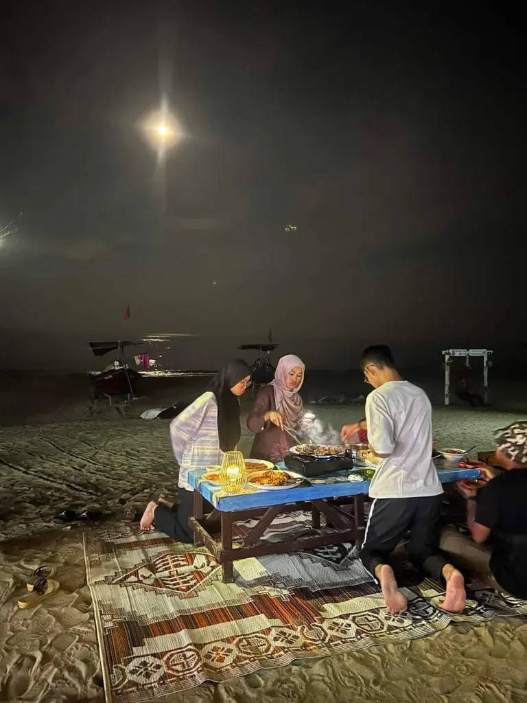 Hidangan steamboat di atas meja di kawasan pantai pada waktu malam