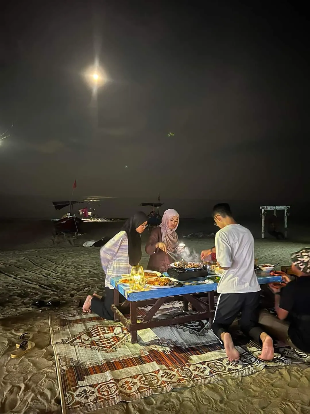 Hidangan steamboat di atas meja di kawasan pantai pada waktu malam